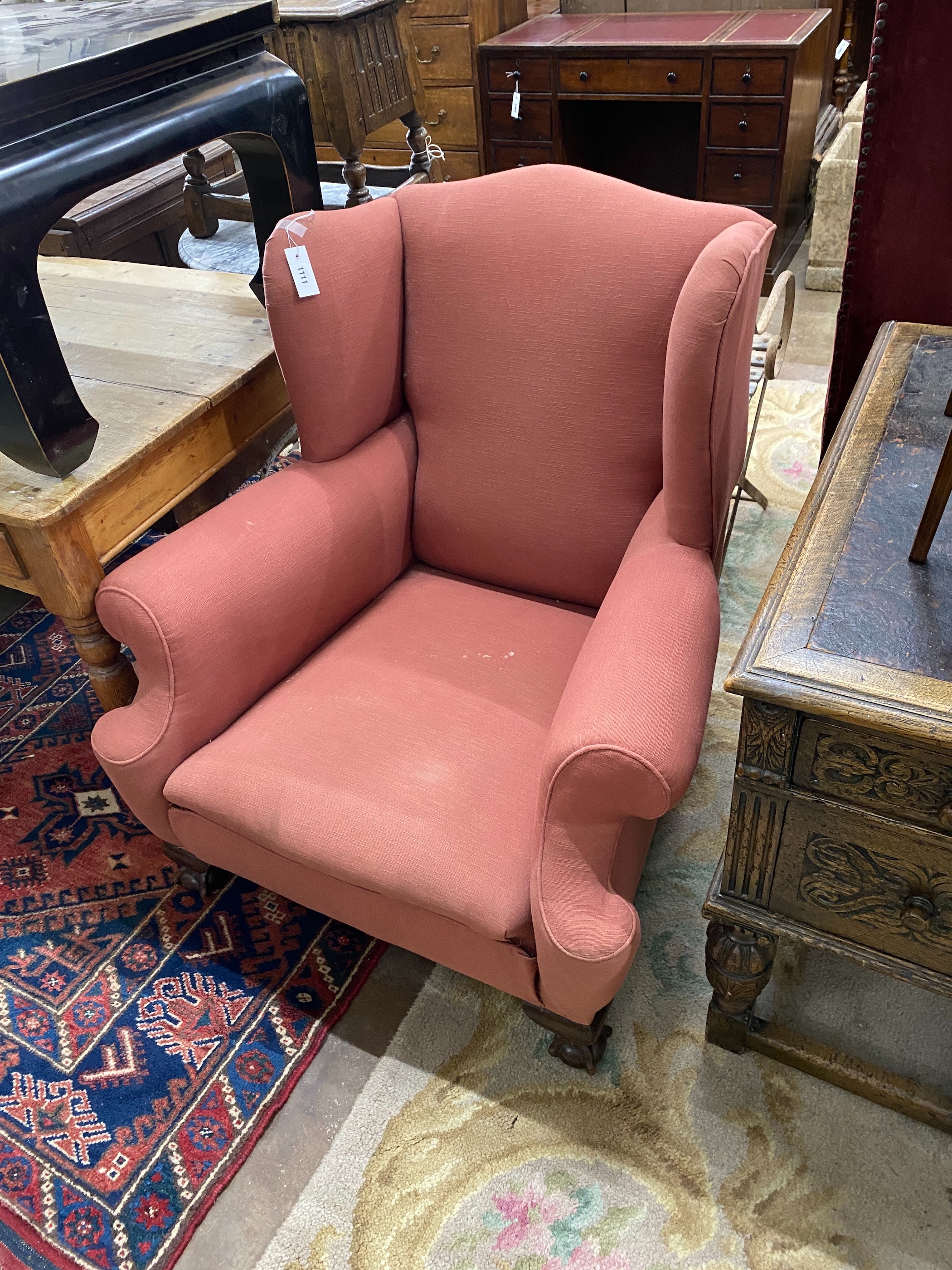An early 20th century upholstered wing armchair, width 88cm, depth 84cm, height 94cm